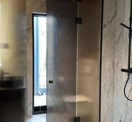 Artesaanilasinen kylpyhuoneen lasiseinä lasiovella-pronssi raita-mustat viimeistelyt-mittatilaus-villa_satakielin-asuntomessut 2025 oulu-kuvaaja charlotta taskinen